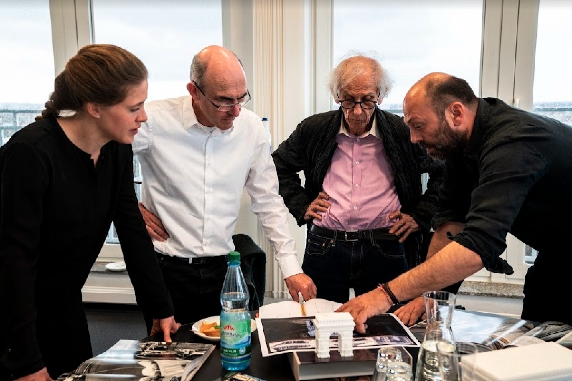 Christo, Prof. Schlaich, and their teams review engineering plans for the substructure of “L’Arc de Triomphe, Wrapped” at the headquarters of Schlaich Bergermann Partner Wolfgang Volz © 2019 Christo and Jeanne-Claude Foundation title=