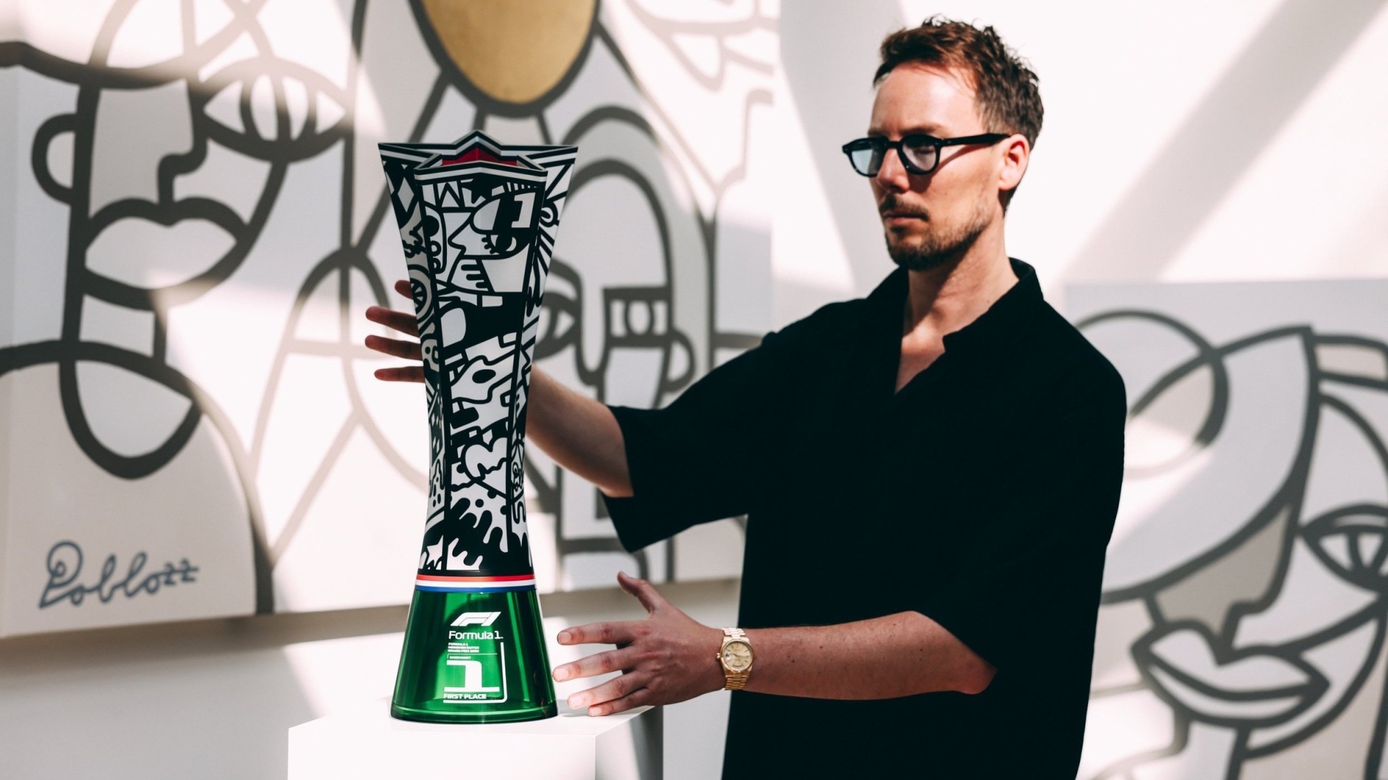 Pablo Lücker with the Formula 1 trophy he designed, a 360-collaboration for which he also designed the race vehicles, race suits, parts of the track, the business lounges, the award ceremony podium, and even the beer bottles. title=